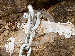 Detail of steel bolt anchor eye in sandstone roc hold steel chain.