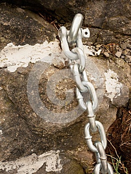 Detail of steel bolt anchor eye in sandstone roc hold steel chain.