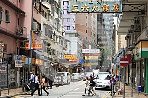 Detail of a street in central Hong Kong with many people walking on the street. On background local shops and restaurants