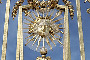 Detail of sun symbol in golden exterior fence at the facade of Versailles Palace, Paris, France