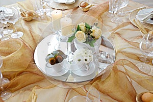 Detail of a table set in ocher color organza for a wedding banquet