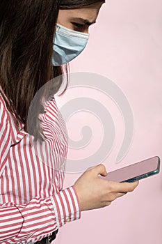 Detail of a teenage girl with long hair red and white striped shirt using smart phone to view photos and send messages with blue