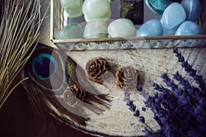 Detail of three pineapples on a wooden trunk next to a glass jewelry box with semiprecious stones in green and turquoise tones.