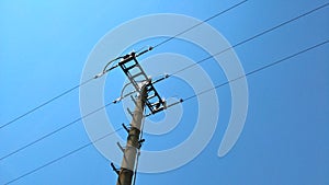 Detail of top part of low voltage pole of local electrical grid seen against blue sky