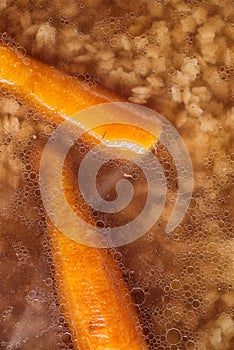 Detail on traditional hot beef roth with vegetable, top view of hot soup with carrot and pasta