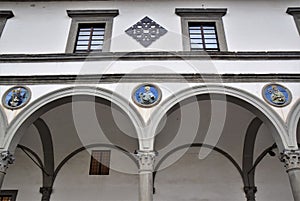 Detail of two arcades, with circles containing colored terracotta sculptures, of the historical building, which is located next to