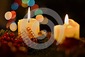 Detail of two burning candles with background made of colorful bokeh lights placed on the Christmas tree