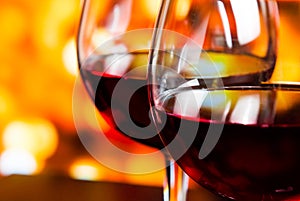 Detail of two red wine glasses against colorful unfocused lights background photo