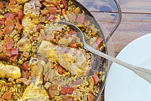 Detail of a typical Spanish paella pan with rice with chicken and saffron or chicken paella, a ladle to serve inside the rice and