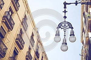 Detail of typical street lamp with facade of old buildings near