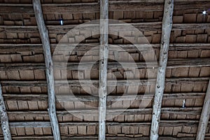 Detail of the underside of a porch roof on an old log cabin with pole beams and wood shingles photo