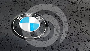 Detail of the vent of a BMW logo on a black car, on a rainy day