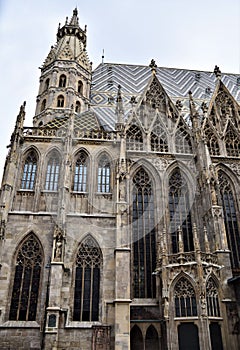 Detail of the Vienna Cathedral. Gothic spiers stand out against the colored tiles and stretch out into the blue sky.