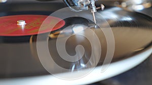 Detail view of black vinyl record spinning on old turntable. Needle sliding smoothly on vintage plate playing music