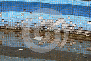 Detail view of blue tiles of an abandoned swimming pool illuminated by the sun