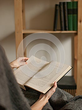 Detail view on book in hands with bookcase in background