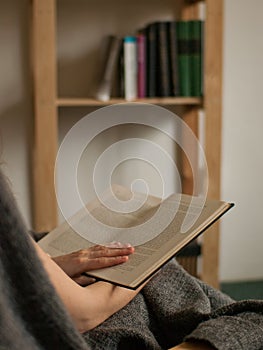 Detail view on book in hands with bookcase in background