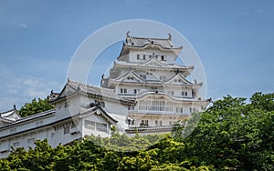 Detail View on Himeji Castle on a clear, sunny day framed by green vegetation. Himeji, Hyogo, Japan, Asia