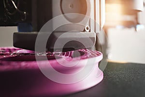 Detail view on nozzle of 3D-printer making a planetary gear part from pink plastic filament.