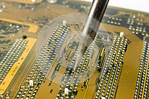 Detail view of soldering iron heating a motherboard component to replace it