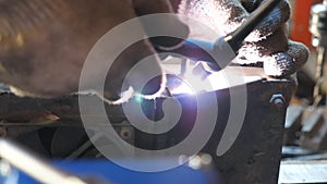 Detail view to welding works in garage or workshop. Mechanic welds some metal parts using professional equipment. Close