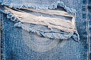 Detail of vintage blue denim jeans torn texture background