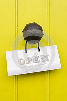 Detail of a vintage brass doorknob with open sign on a bright ye