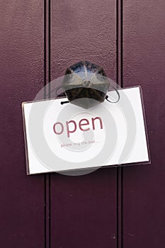 Detail of a vintage brass doorknob with open sign on a dark purple wooden door