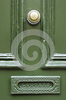 Detail of vintage green wooden door with brass doorknob knocker