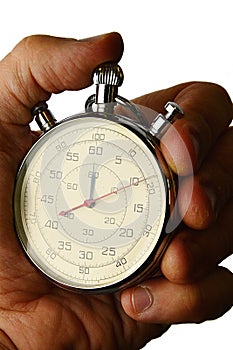 Detail of vintage mechanical wind up stop watch held in left hand with fingers on reset positions, white background