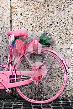 Detail of vintage pink and violet colored bicycle decorated with lavender flowers and lilac ribbons deco