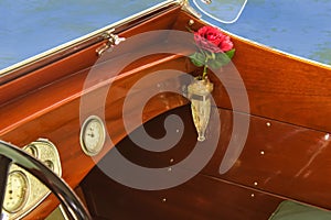 Detail of vintage wooden speed boat with crystal vase in vase holder with a red rose