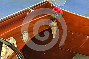 Detail of vintage wooden speed boat with crystal vase in vase holder with a red rose in it