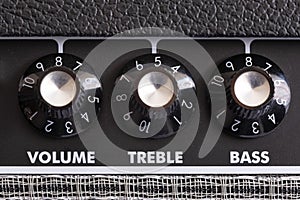 Detail of the volume, treble and bass control knobs of a guitar amplifier, equalization dials close up, selective focus