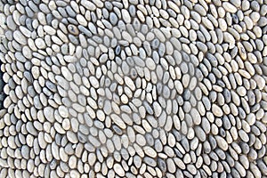 Detail of a walkway made of river pebbles, stone background, light grey and white colors