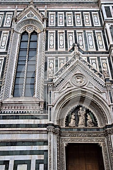 Detail of the wall of the cathedral Santa Maria del Fiore, a door with above the statue of the Madonna with Child in her arms and