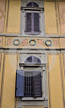 Detail of the wall of Villa Stibbert overlooking the park. The image shows two windows and three colored crowns.