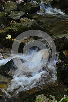 Detail prúdenia vody v čistom horskom potoku, fotografovaný s dlhším záberom.