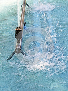 Detail of water jet spout in fountain with blue water and reflections. Blue water background with jet splash and mist. Pulsating