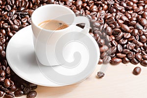 Detail of white cup with espresso coffee near coffee beans