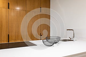 Detail of white kitchen interior with wooden furniture. Countertop with stove and decorative bowls for fruits.