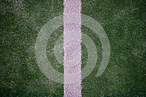 detail of white line detail painted on green artificial synthetic grass with sand dirt