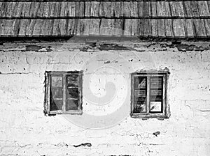 Detail with a white painted old rustic romanian house. Two wooden windows of a traditional romanian house