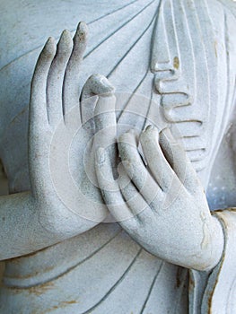 Detail of a white statue of the Buddha with his hands. Fingers in mudra