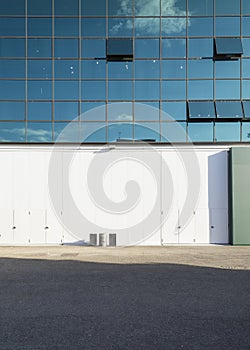 Detail of a white wall with a large glass window above. Front view, urban architecture, nobody around