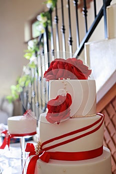 Detail of white wedding cake with red edible flowers