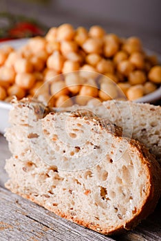 Detail of wholewheat bread in front of bowl with chickpeas