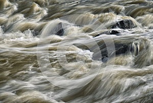 Detail of wild muddy river with rapids