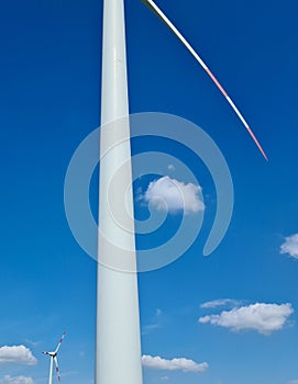 Detail of wind power plant post in blue sky with clouds