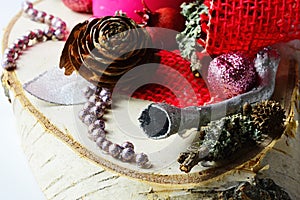 Detail of winter christmas decoration with trumpet shaped silver painted piece of wood, red fabric, shiny beads, cones and lichen